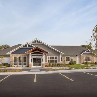 A suburban residential building with a parking lot in front, captured during the daytime.