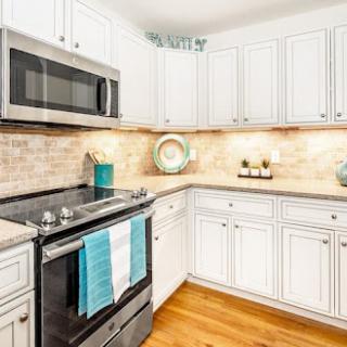 A bright and modern kitchen featuring white cabinetry, stainless steel appliances, and stylish blue accents.