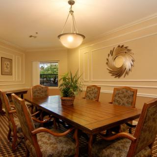 A well-decorated conference room with a large wooden table, upholstered chairs, and elegant lighting.