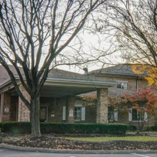 A brick building entrance surrounded by trees in autumn.