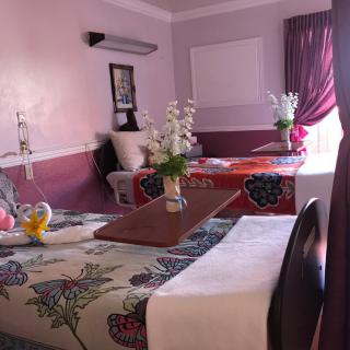 A cozy hotel room with beautifully decorated beds and fresh flowers.