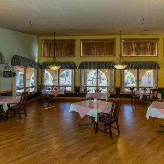 An empty restaurant dining room with neatly arranged tables and chairs on a wooden floor.