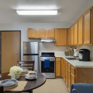 A cozy kitchen with wooden cabinets, a dining table set, and modern appliances.
