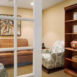 A cozy living room with a sofa, armchair, and a wooden bookshelf.