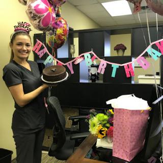 A joyful birthday celebration in the office with decorations, balloons, and gifts.