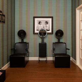 Vintage salon interior with hair dryer chairs and framed photo on the wall.