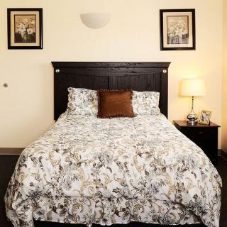 A cozy bedroom with a patterned bedspread and bedside lamp.