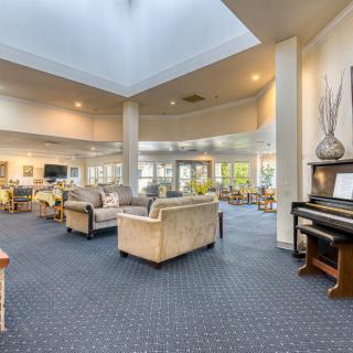 Spacious and elegant lobby with modern furnishings and a piano, illuminated by natural light.