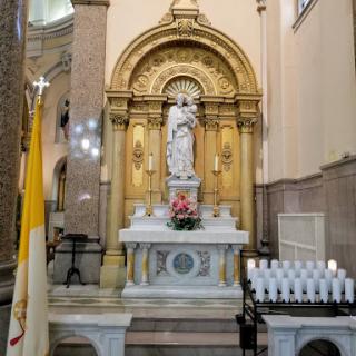 A beautifully adorned altar featuring a statue surrounded by candles, reflecting the serene atmosphere of a place of worship.