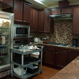 A modern kitchen with dark wood cabinets, stainless steel appliances, and a mobile kitchen cart.