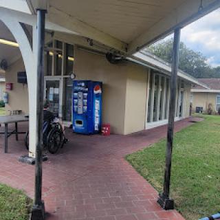 A vending machine situated outside a building with a brick pathway and grassy area.