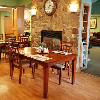 A cozy dining area with wooden furniture and a stone fireplace.