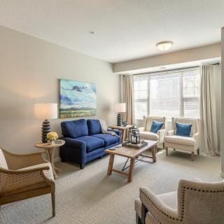 A cozy and well-lit living room with a blue sofa, armchairs, and a coffee table.