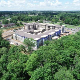 Aerial view of a building under construction surrounded by lush greenery.