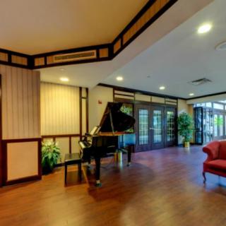 A modern lobby with a grand piano, wood flooring, and comfortable seating.