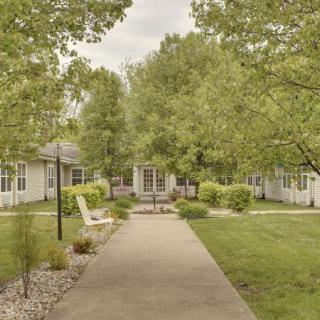 A serene outdoor pathway surrounded by lush greenery and buildings.