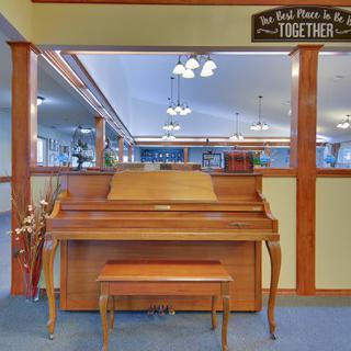 A cozy music room featuring a piano and bench, adorned with a motivational sign.