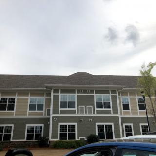 A modern multi-family residential building under a cloudy sky.