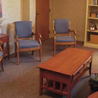 A cozy waiting room with blue upholstered chairs and a wooden coffee table.