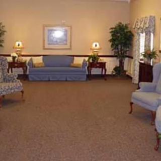 A cozy living room with sofas, chairs, and decorative plants.