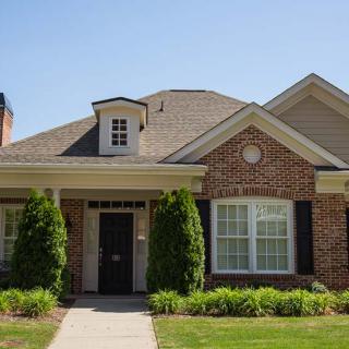 A charming suburban brick house with a manicured front yard.