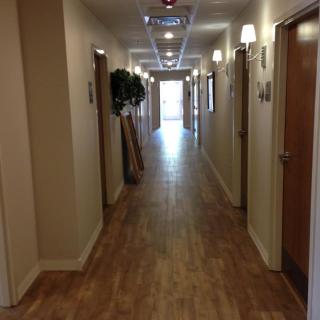 A long, well-lit hallway with wooden flooring and doors on either side.