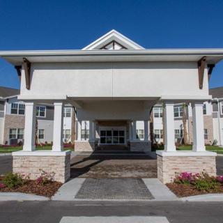 A modern residential building with a covered entrance and columns against a clear blue sky.