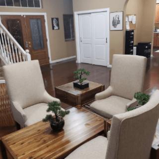 A cozy living room setup with comfortable chairs, wooden tables, and small indoor plants.