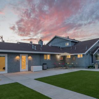 A suburban house with a spacious yard at twilight, under a colorful sky.