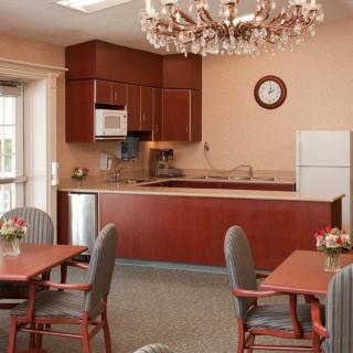 A cozy kitchen and dining area featuring wooden cabinets, a chandelier, and several tables with chairs.