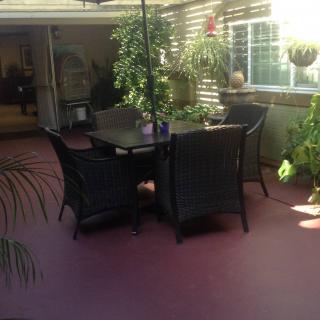 A cozy outdoor patio with a dining set surrounded by lush plants.