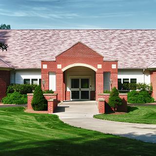 A brick building with a landscaped lawn and pathway leading to its entrance.