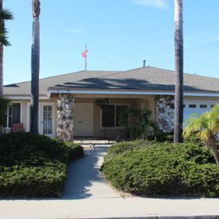 A suburban house with palm trees and well-maintained landscaping.
