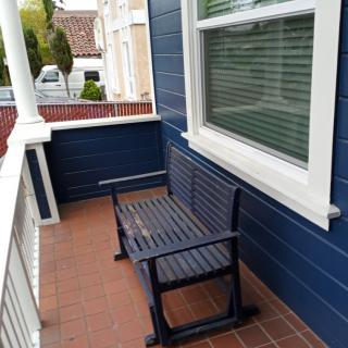 A small porch with a blue wall and a wooden bench.