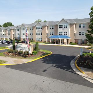 A welcoming residential building with a blue roof surrounded by landscaped grounds.