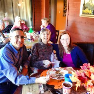 A group of people enjoying a meal together indoors, smiling and celebrating togetherness.