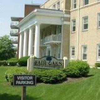 A building with columns at the entrance, featuring a sign for visitors parking.
