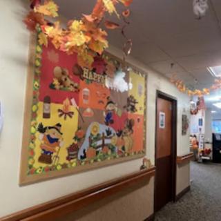 A hallway adorned with fall-themed decorations and a colorful bulletin board celebrating autumn.