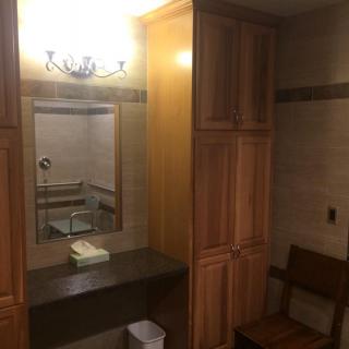 A bathroom featuring a mirror, sink, and wooden cabinets under soft lighting.