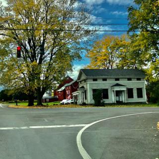 A picturesque rural intersection showcasing vibrant fall colors and a mix of charming houses.
