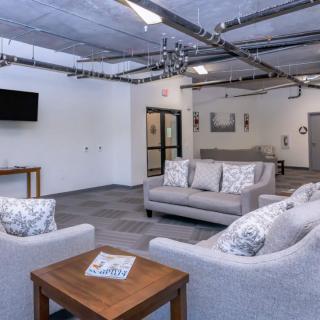 A modern living room with industrial elements featuring gray sofas, a coffee table, and a wall-mounted TV.