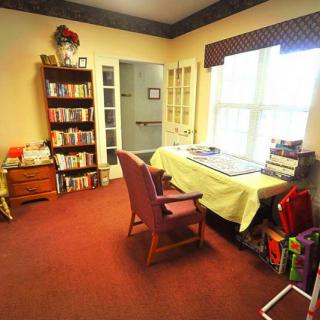 A cozy living room with a desk, chair, and bookshelf filled with books.