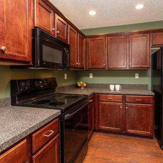 A modern kitchen with wooden cabinets and essential appliances.