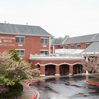 A brick hotel building with a welcoming entrance and surrounding trees.