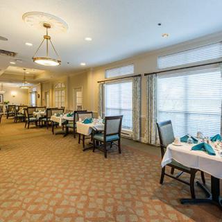 An elegant dining room with neatly arranged tables and chairs, featuring white tablecloths and folded napkins.