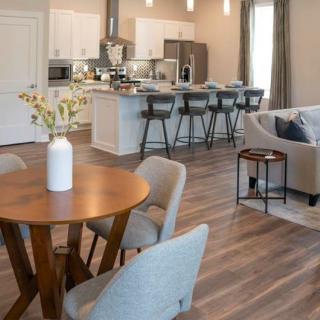 A modern open-concept interior featuring a kitchen, living room, and dining area with sleek furnishings and wood flooring.