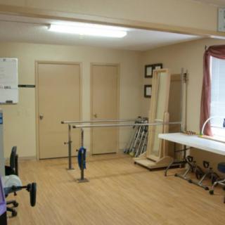 A physical therapy room with parallel bars and various exercise equipment.