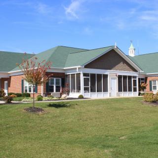 A residential building with a green roof and well-maintained lawn under a clear blue sky.