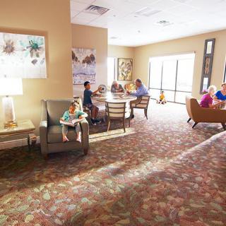 A cozy living room setting with people socializing and relaxing on armchairs and sofas.