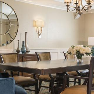 A well-decorated dining room with a large table, chairs, and elegant lighting.